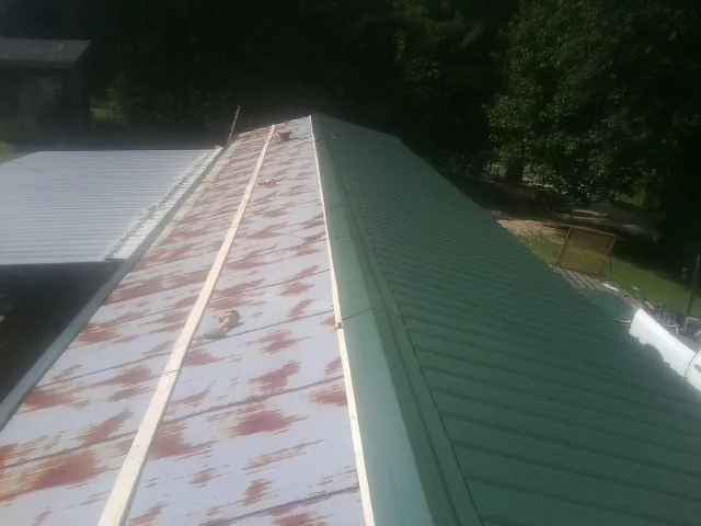 Old rusted panels beside newly installed green metal roofing — Wind Damage Roof Repair by Roofing Brothers in Hernando